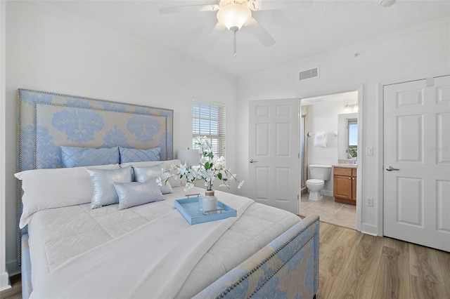 bedroom with crown molding, ceiling fan, connected bathroom, and light hardwood / wood-style flooring