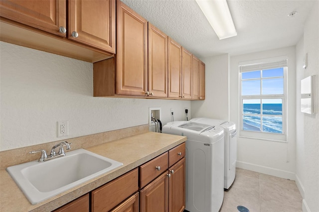 laundry room featuring separate washer and dryer, sink, cabinets, a water view, and a textured ceiling