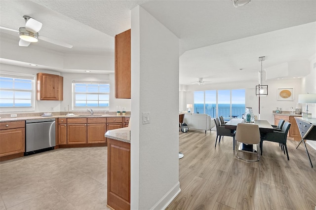 kitchen with decorative light fixtures, dishwasher, sink, ceiling fan, and a water view