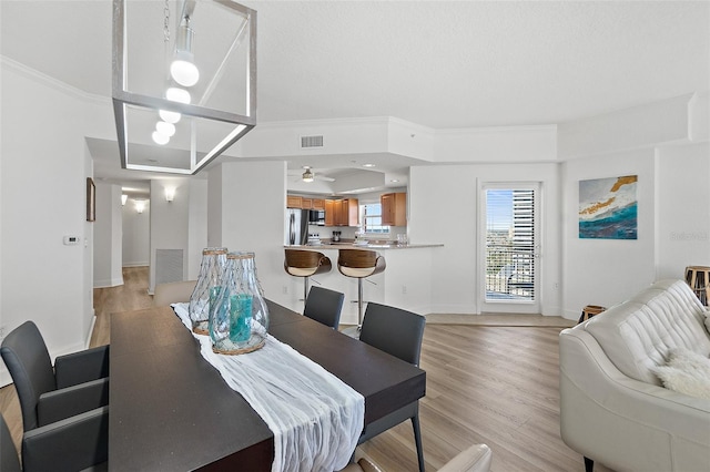 dining space with crown molding and light hardwood / wood-style floors