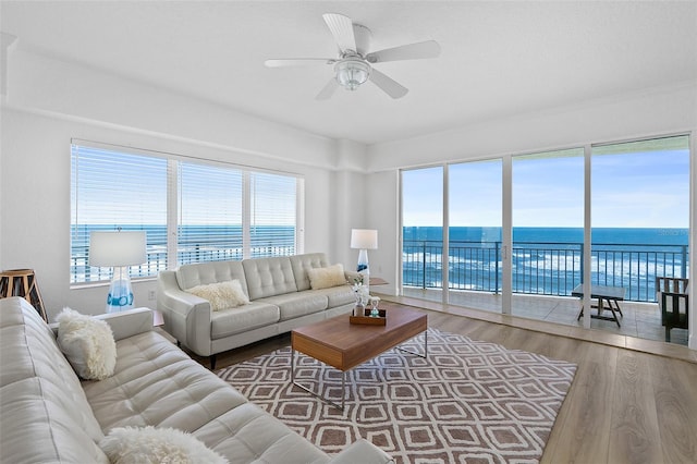 living room featuring wood-type flooring, a water view, and ceiling fan