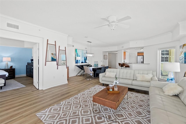 living room with crown molding, wood-type flooring, and ceiling fan