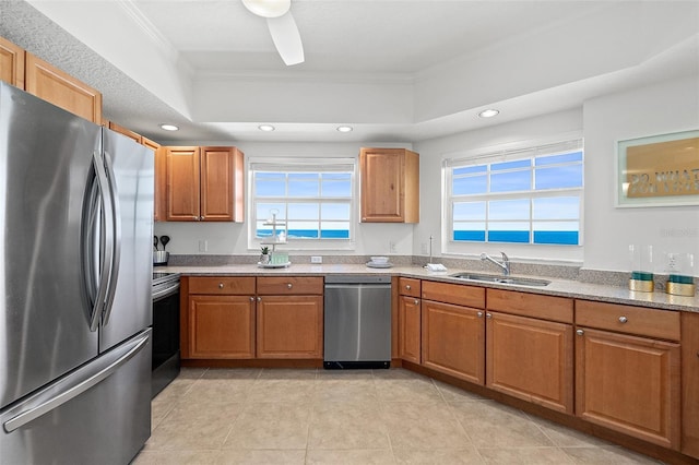 kitchen with sink, appliances with stainless steel finishes, light stone counters, ornamental molding, and a healthy amount of sunlight