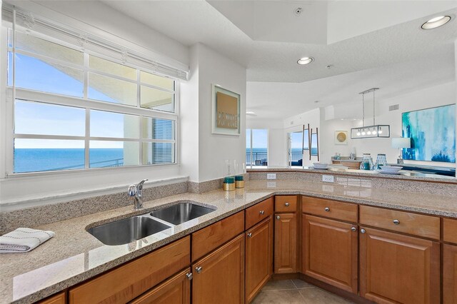 kitchen featuring a water view, sink, a wealth of natural light, and light stone counters