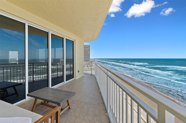 balcony with a water view and a view of the beach