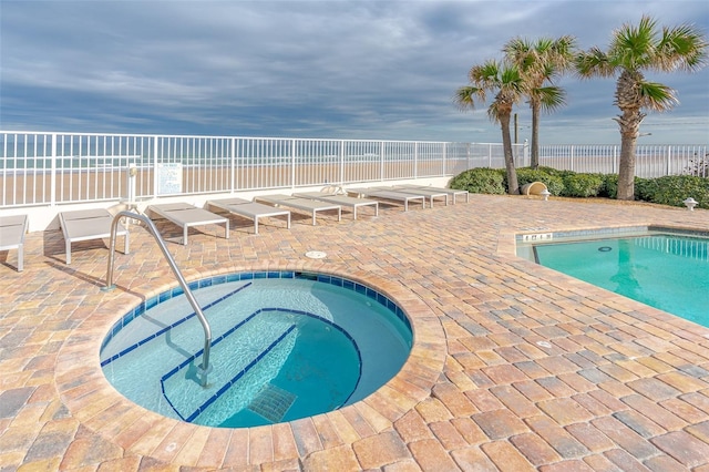 view of swimming pool with a patio, a water view, and a community hot tub