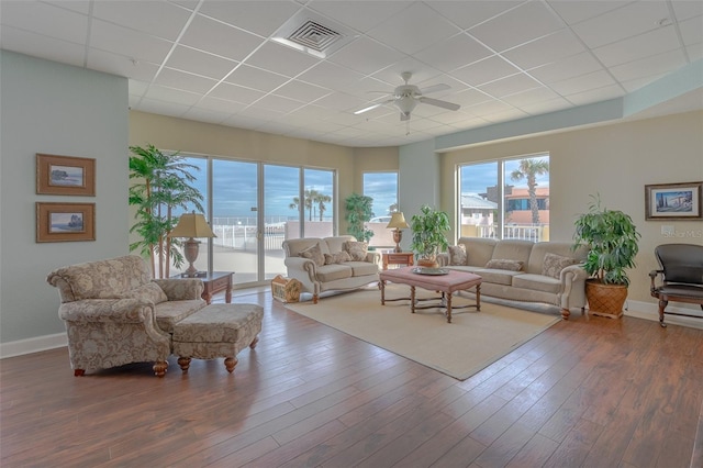 living room with a drop ceiling, dark wood-type flooring, ceiling fan, and a water view