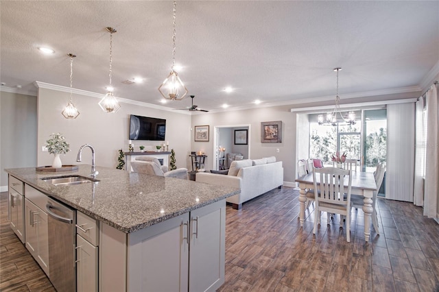 kitchen with hanging light fixtures, light stone counters, stainless steel dishwasher, sink, and a kitchen island with sink