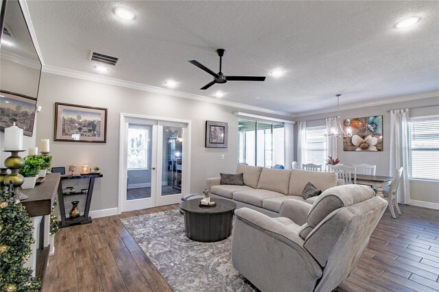 living room featuring ceiling fan with notable chandelier, crown molding, dark hardwood / wood-style floors, and a textured ceiling