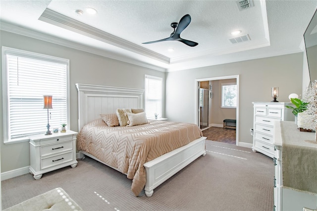 bedroom featuring light colored carpet, ornamental molding, ceiling fan, a raised ceiling, and a textured ceiling