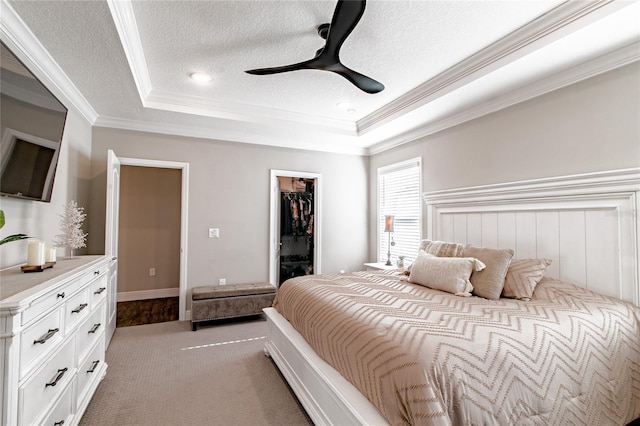 bedroom featuring ornamental molding, a raised ceiling, a textured ceiling, and a spacious closet