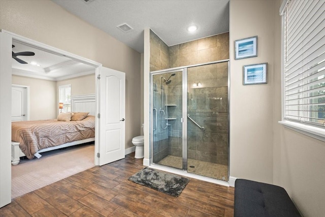 bathroom featuring hardwood / wood-style floors, crown molding, toilet, and a shower with door