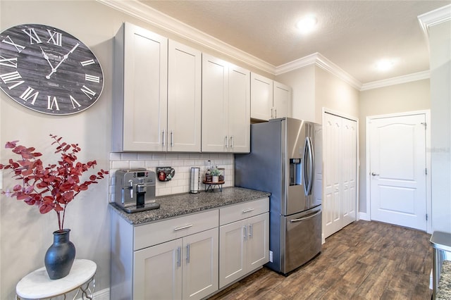 kitchen featuring crown molding, backsplash, dark hardwood / wood-style flooring, stainless steel fridge with ice dispenser, and dark stone countertops