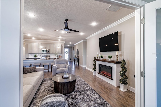 living room featuring hardwood / wood-style flooring, ornamental molding, a textured ceiling, and ceiling fan