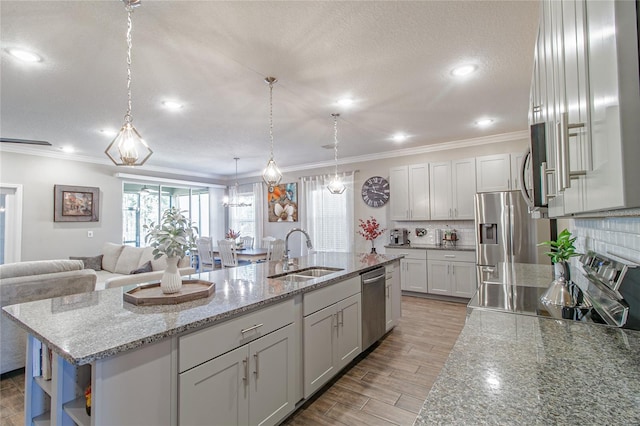 kitchen featuring a center island with sink, decorative light fixtures, sink, and stainless steel appliances