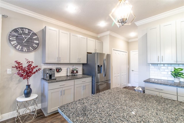 kitchen featuring crown molding, dark stone counters, stainless steel refrigerator with ice dispenser, and dark hardwood / wood-style floors