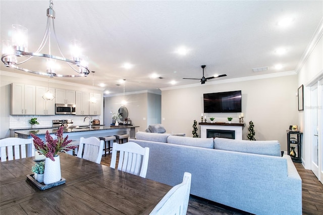 dining room featuring crown molding, sink, dark wood-type flooring, and ceiling fan