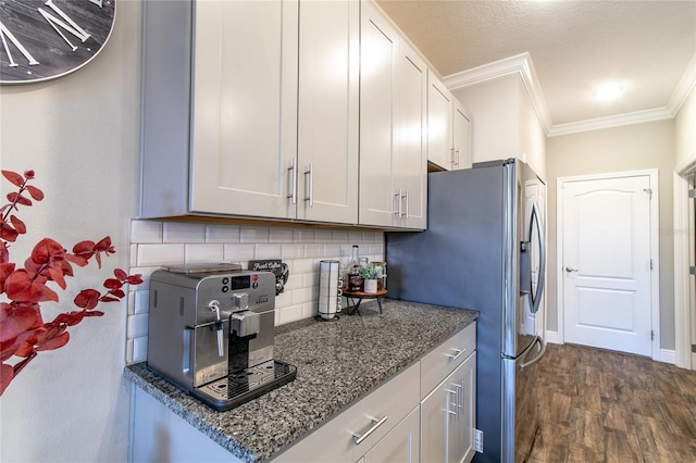 kitchen with dark stone countertops, white cabinetry, crown molding, dark hardwood / wood-style flooring, and decorative backsplash