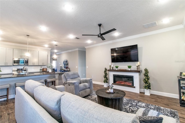 living room featuring ceiling fan, a textured ceiling, dark hardwood / wood-style flooring, and ornamental molding