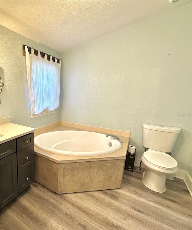 bathroom featuring toilet, a textured ceiling, a garden tub, and wood finished floors