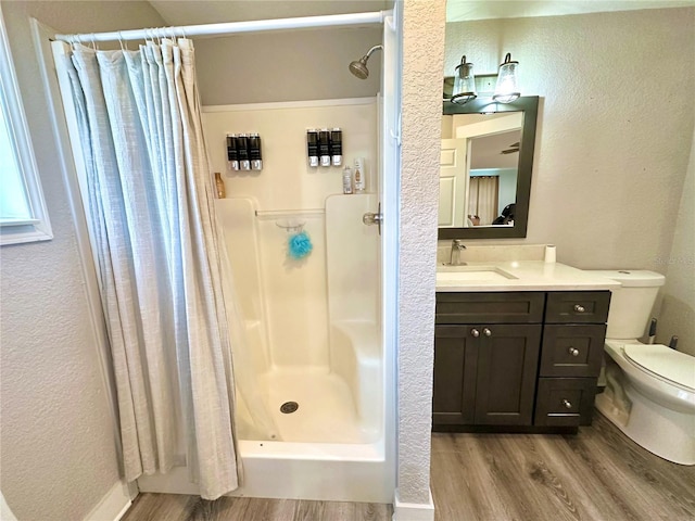 bathroom featuring a shower stall, toilet, and wood finished floors