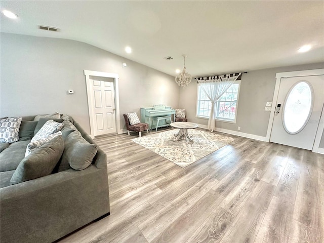 living room with lofted ceiling, wood finished floors, visible vents, and baseboards