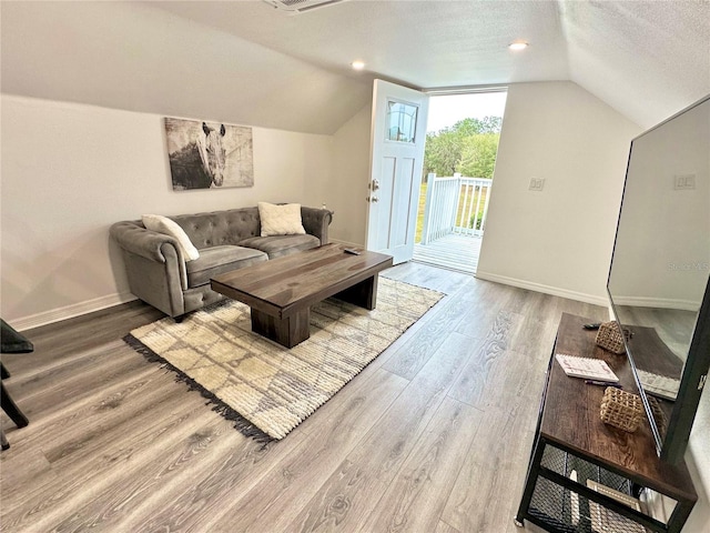 living area featuring a textured ceiling, baseboards, lofted ceiling, and wood finished floors