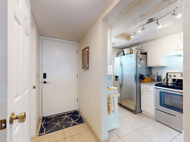 kitchen featuring light tile patterned floors, appliances with stainless steel finishes, track lighting, a textured ceiling, and white cabinets