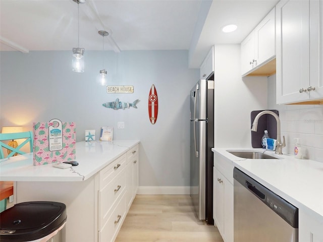 kitchen featuring sink, white cabinetry, hanging light fixtures, appliances with stainless steel finishes, and decorative backsplash