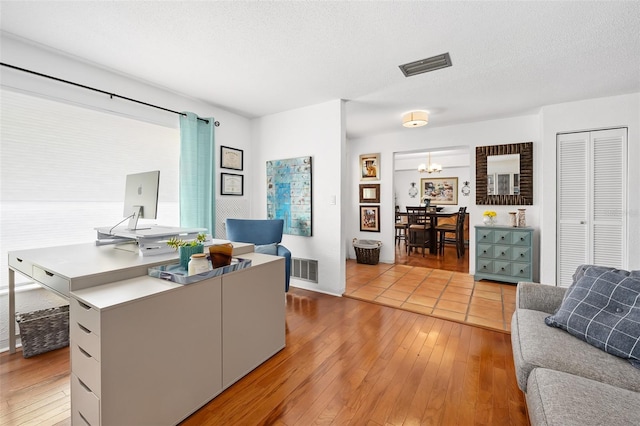 office space featuring an inviting chandelier, light hardwood / wood-style flooring, and a textured ceiling