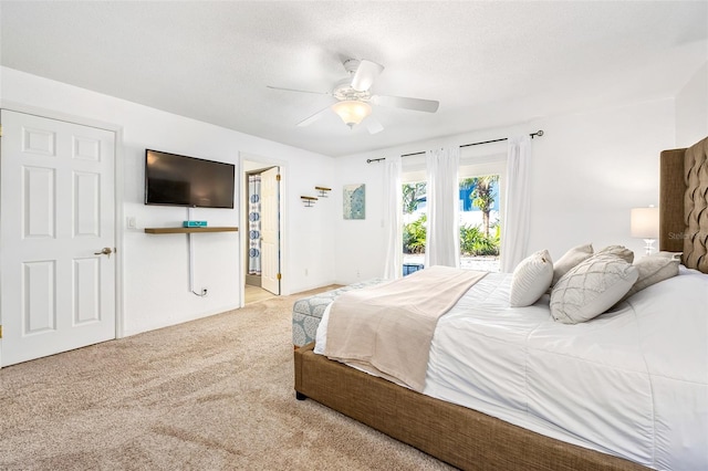 bedroom featuring light carpet, access to outside, a textured ceiling, and ceiling fan