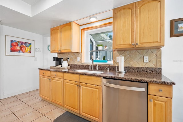 kitchen with tasteful backsplash, dishwasher, sink, dark stone counters, and light tile patterned floors