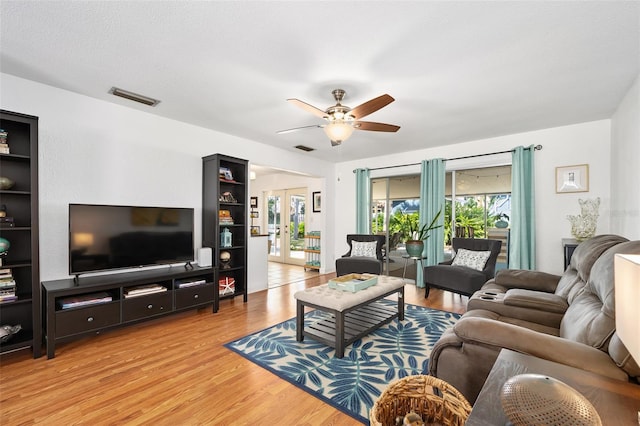 living room featuring ceiling fan, a textured ceiling, light hardwood / wood-style floors, and french doors