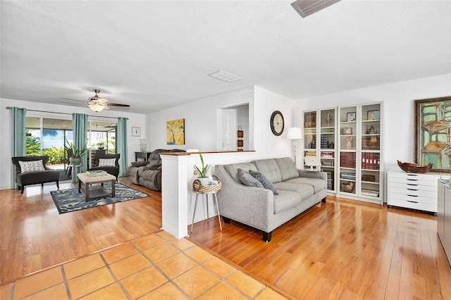 living room featuring ceiling fan, a textured ceiling, and light hardwood / wood-style floors