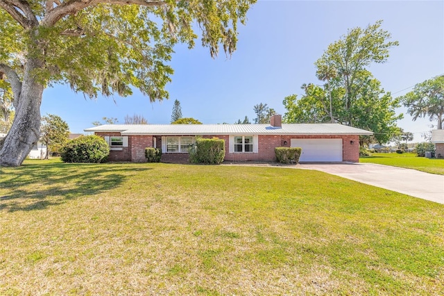 ranch-style house featuring driveway, a front yard, an attached garage, brick siding, and a chimney