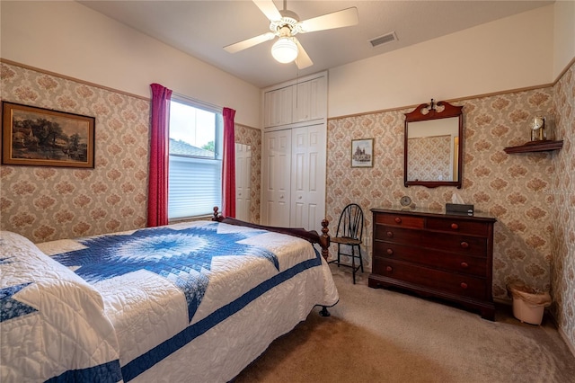 carpeted bedroom featuring wallpapered walls, ceiling fan, visible vents, and a closet