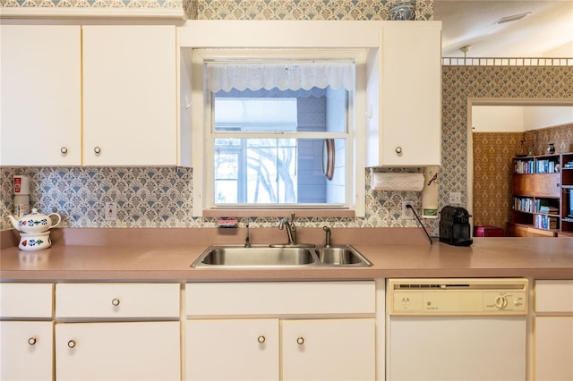 kitchen with a sink, white cabinets, light countertops, backsplash, and dishwasher