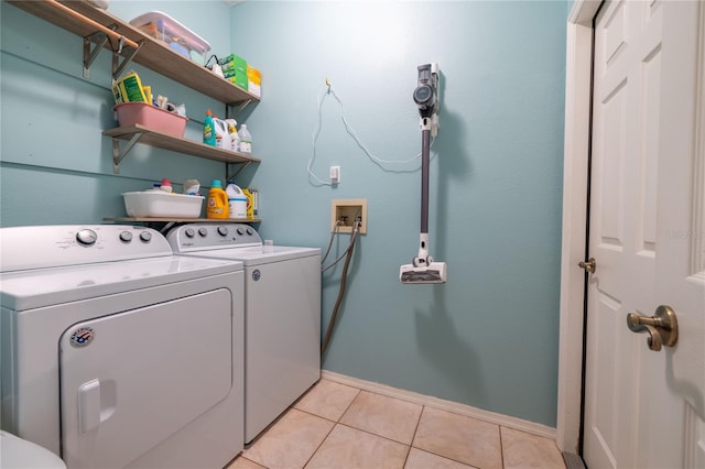 laundry room with laundry area, washing machine and dryer, light tile patterned floors, and baseboards