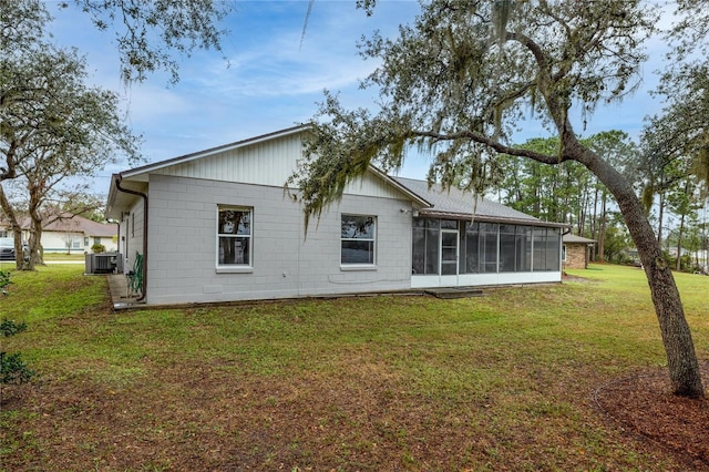 rear view of property featuring a sunroom, cooling unit, and a lawn