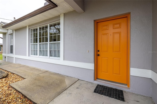 doorway to property featuring visible vents and stucco siding