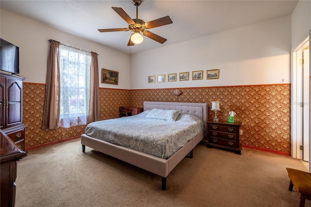 bedroom featuring a wainscoted wall, ceiling fan, carpet flooring, and wallpapered walls