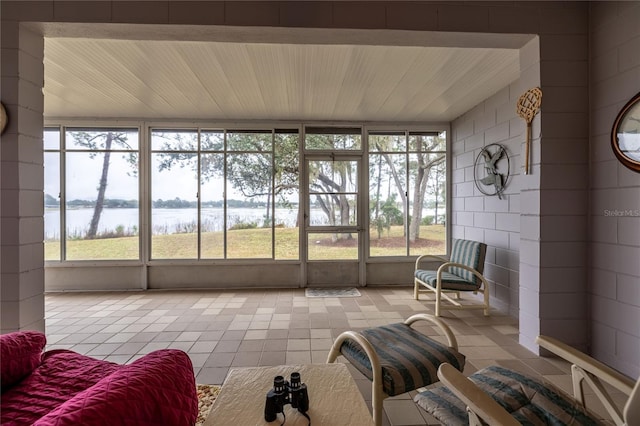 sunroom featuring a water view