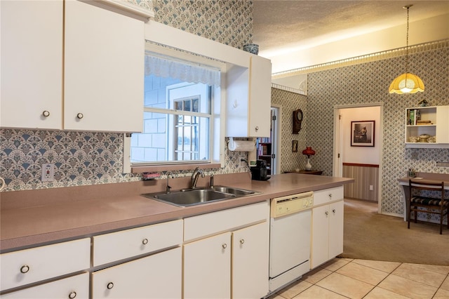 kitchen featuring white dishwasher, a sink, and wallpapered walls