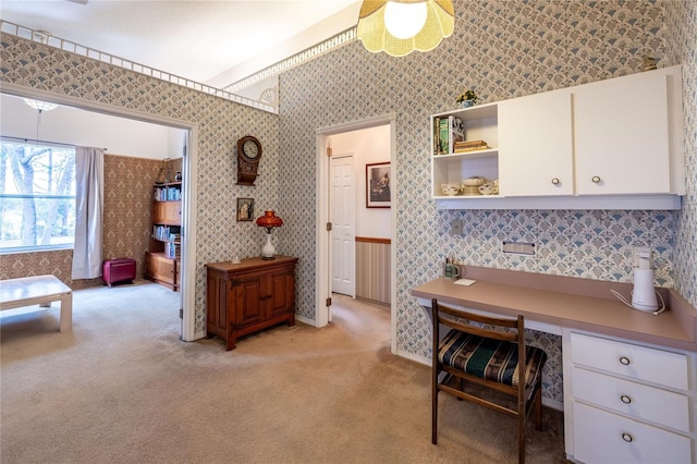 office space featuring built in study area, light colored carpet, and wallpapered walls