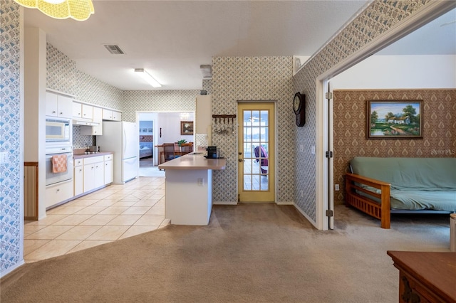 kitchen featuring light carpet, wallpapered walls, visible vents, freestanding refrigerator, and a peninsula