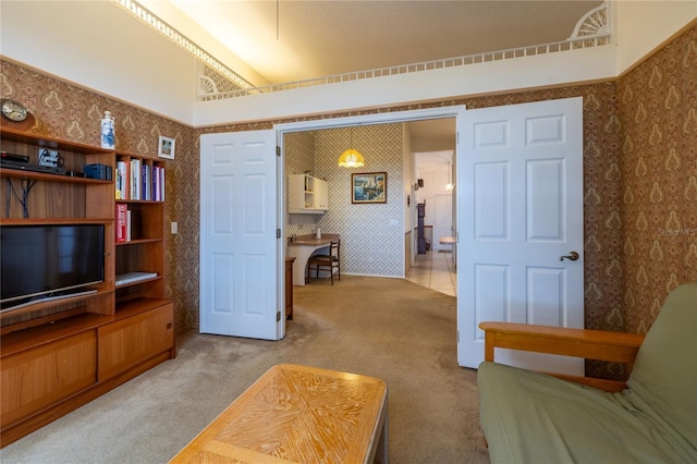 sitting room featuring vaulted ceiling, carpet, and wallpapered walls