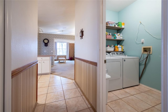 clothes washing area featuring a wainscoted wall, laundry area, separate washer and dryer, and light tile patterned floors