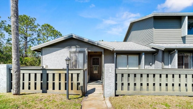 view of front of home with stucco siding and fence