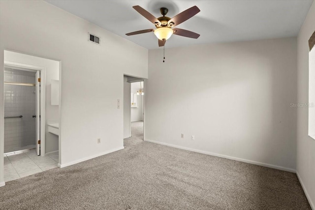 unfurnished bedroom with baseboards, visible vents, carpet floors, ensuite bath, and tile patterned flooring