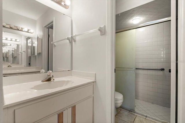 bathroom featuring tile patterned flooring, a shower stall, toilet, and vanity